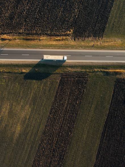 Aerial view of freight transportation truck on the road through countryside