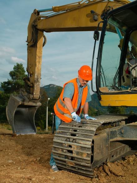 male construction worker repairing excavator track